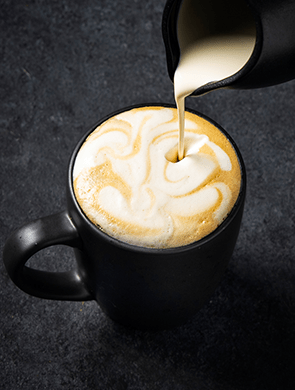 Cup of coffee with a jug pouring Violife dairy-free coffee creamer