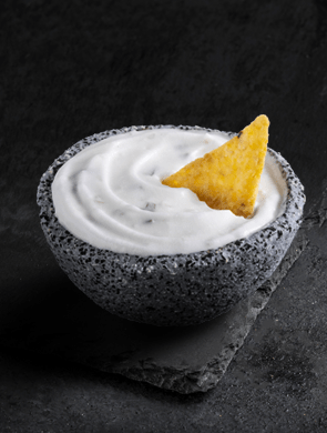 Violife dairy-free dip in a bowl with a tortilla chip inside