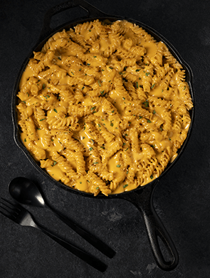 Fusilli pasta in a skillet with cheesy sauce made from Violife dairy-free cheese shreds