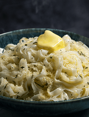 Bowl of tagliatelle topped with Violife dairy free Parmesan and a chunk of plant butter